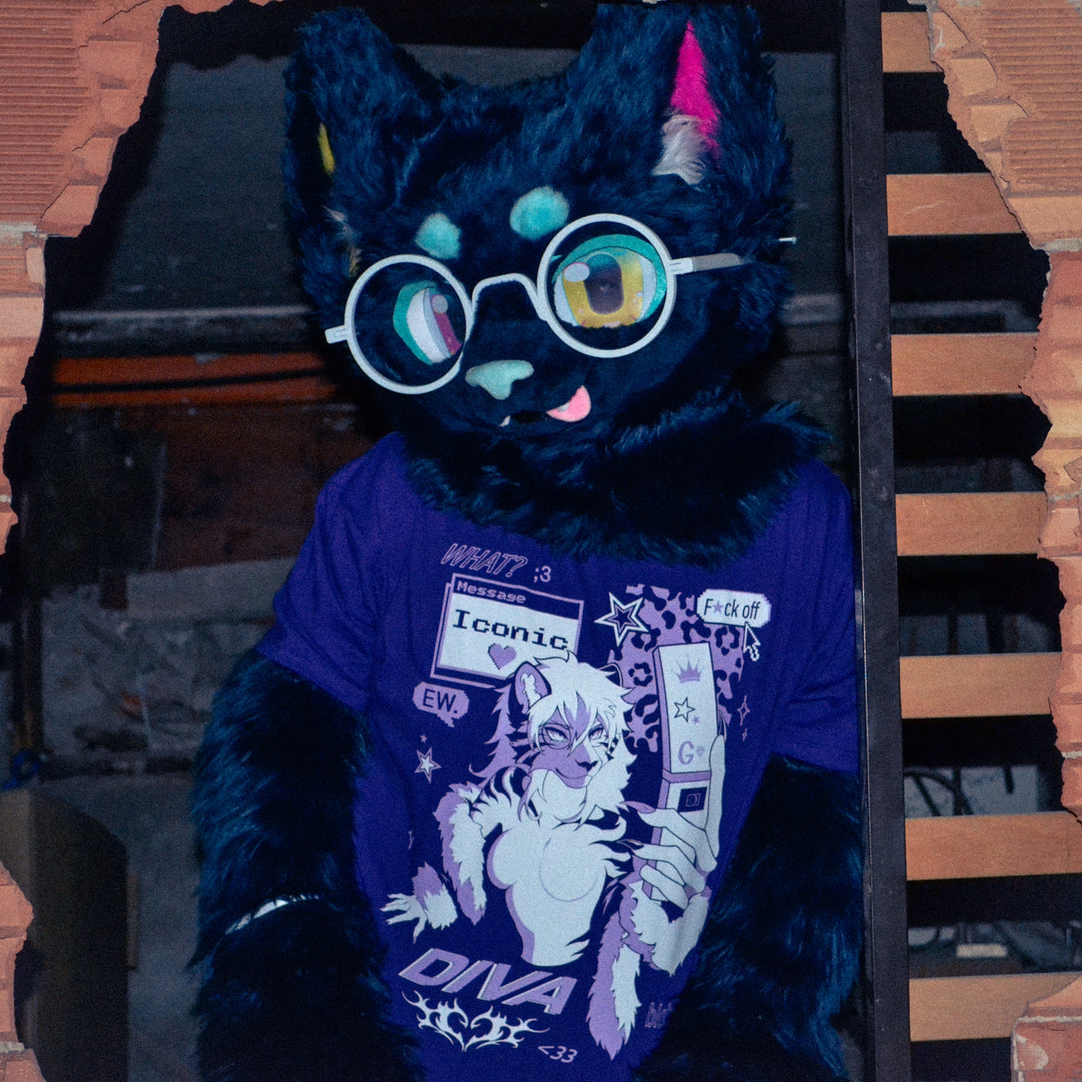A black furry character wearing round white-framed glasses and a purple graphic T-shirt, posed in front of a dark doorway with brick-like framing.
